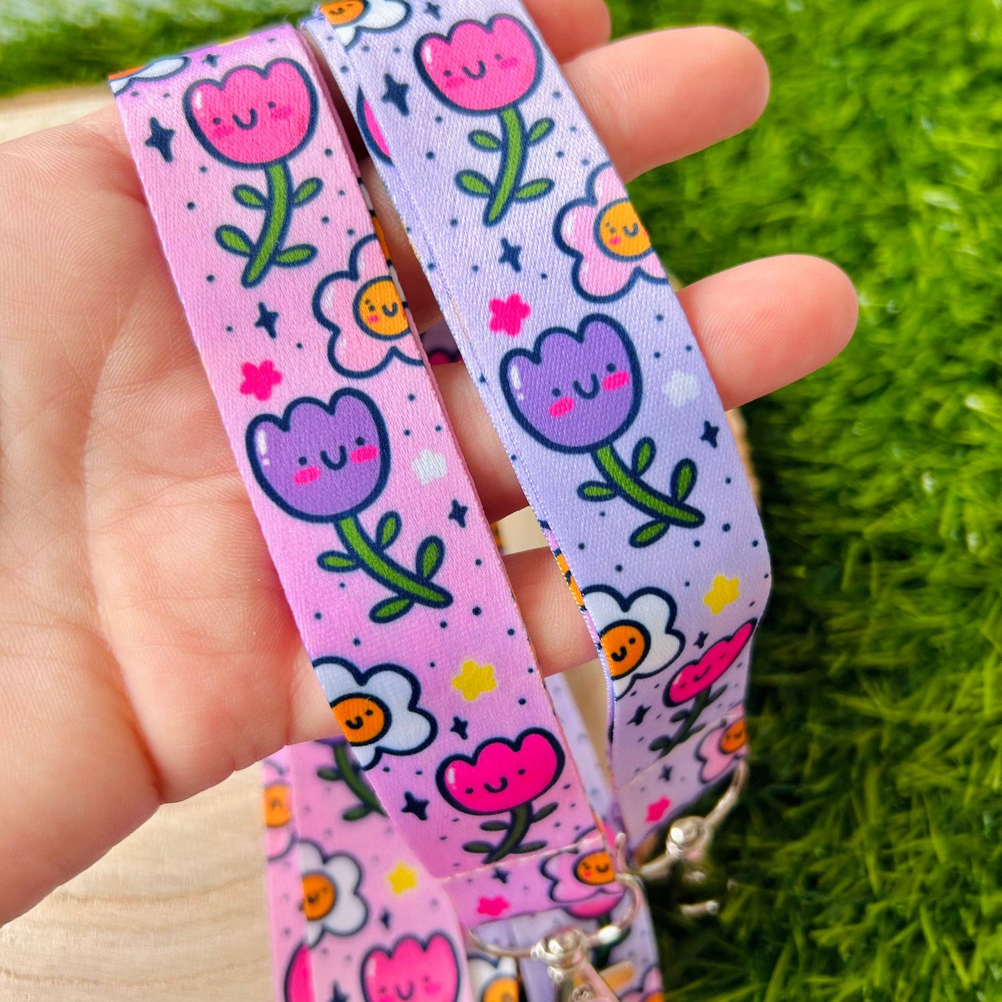 Floral-patterned lanyard held by a hand on grass