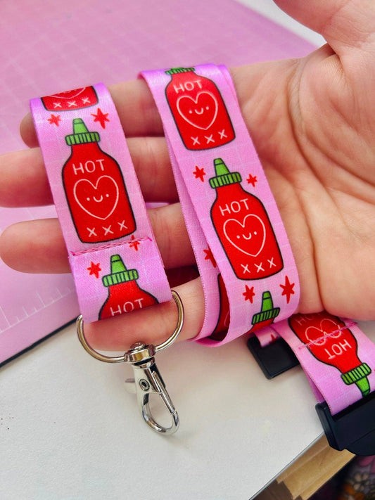 Pink lanyard with hot sauce design held by a hand