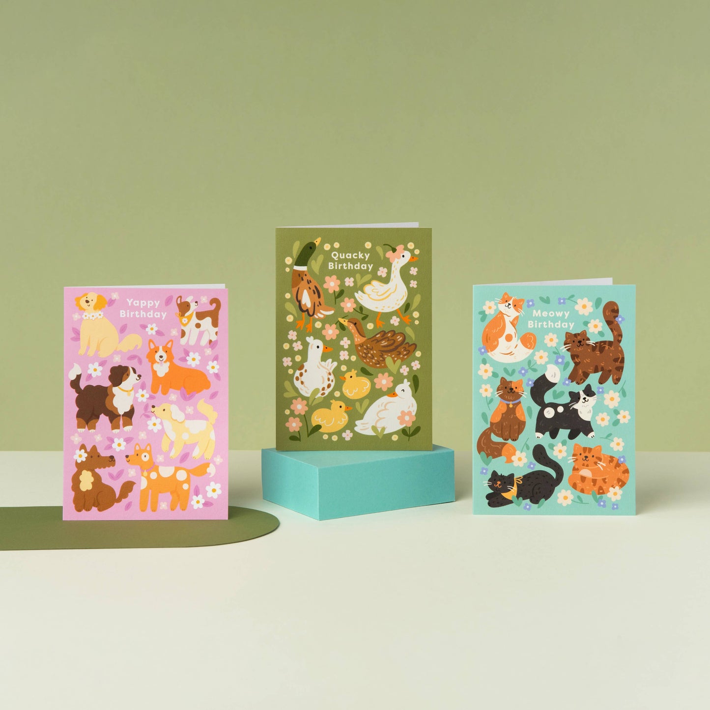 Three colorful greeting cards with animal illustrations on a light green background