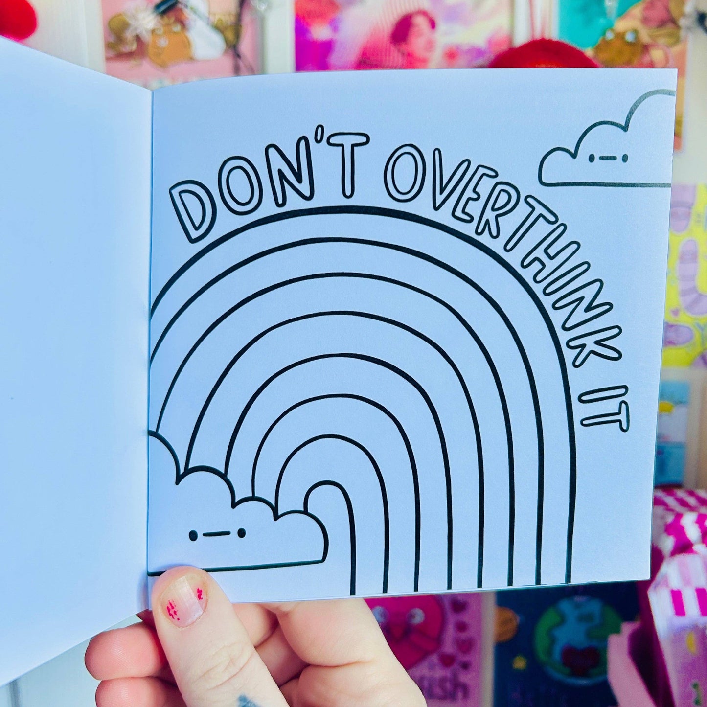 Card with rainbow design and 'Don't Overthink It' text held by a hand.