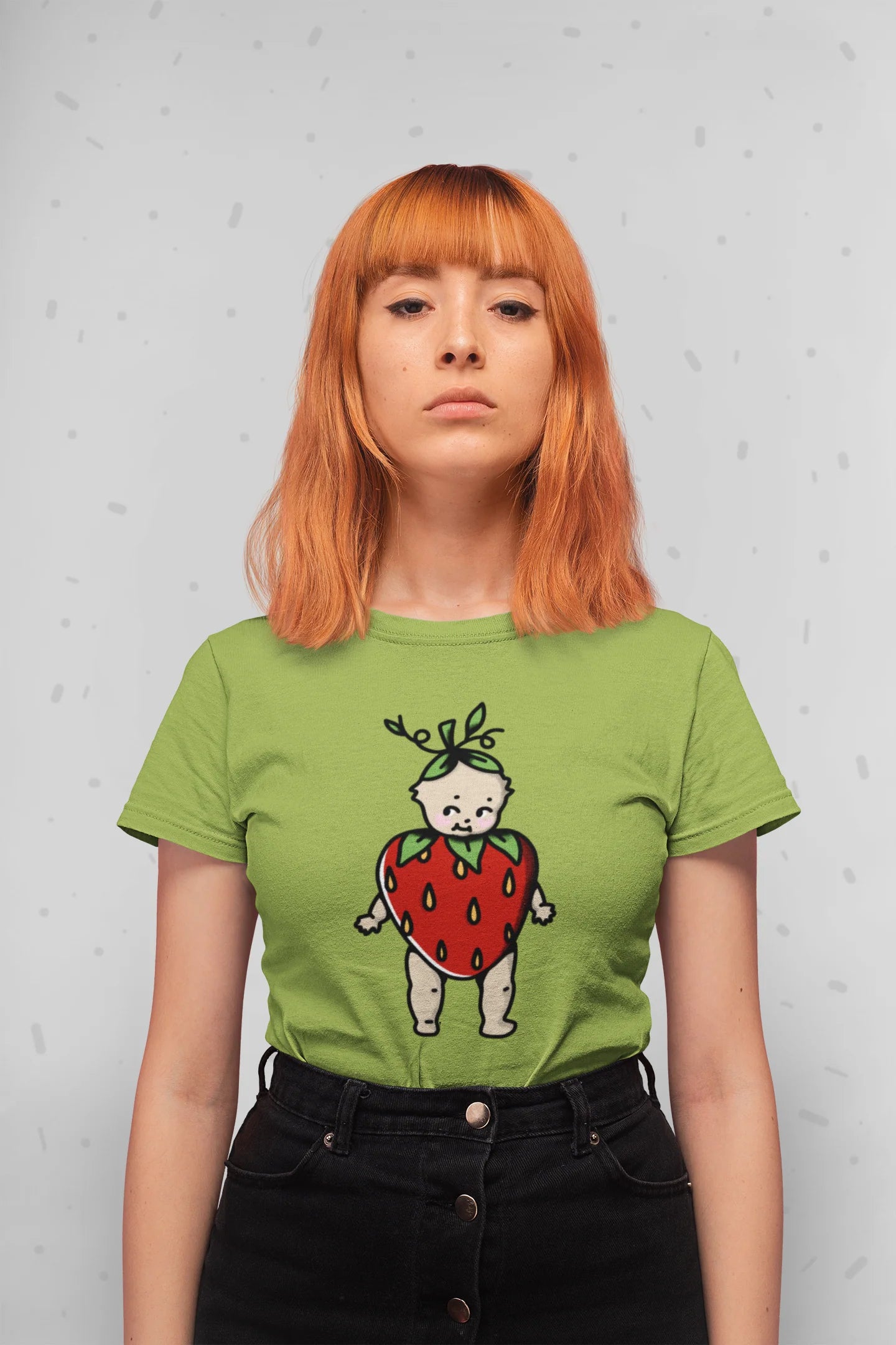 Person wearing a green t-shirt with a strawberry-themed design against a light gray background