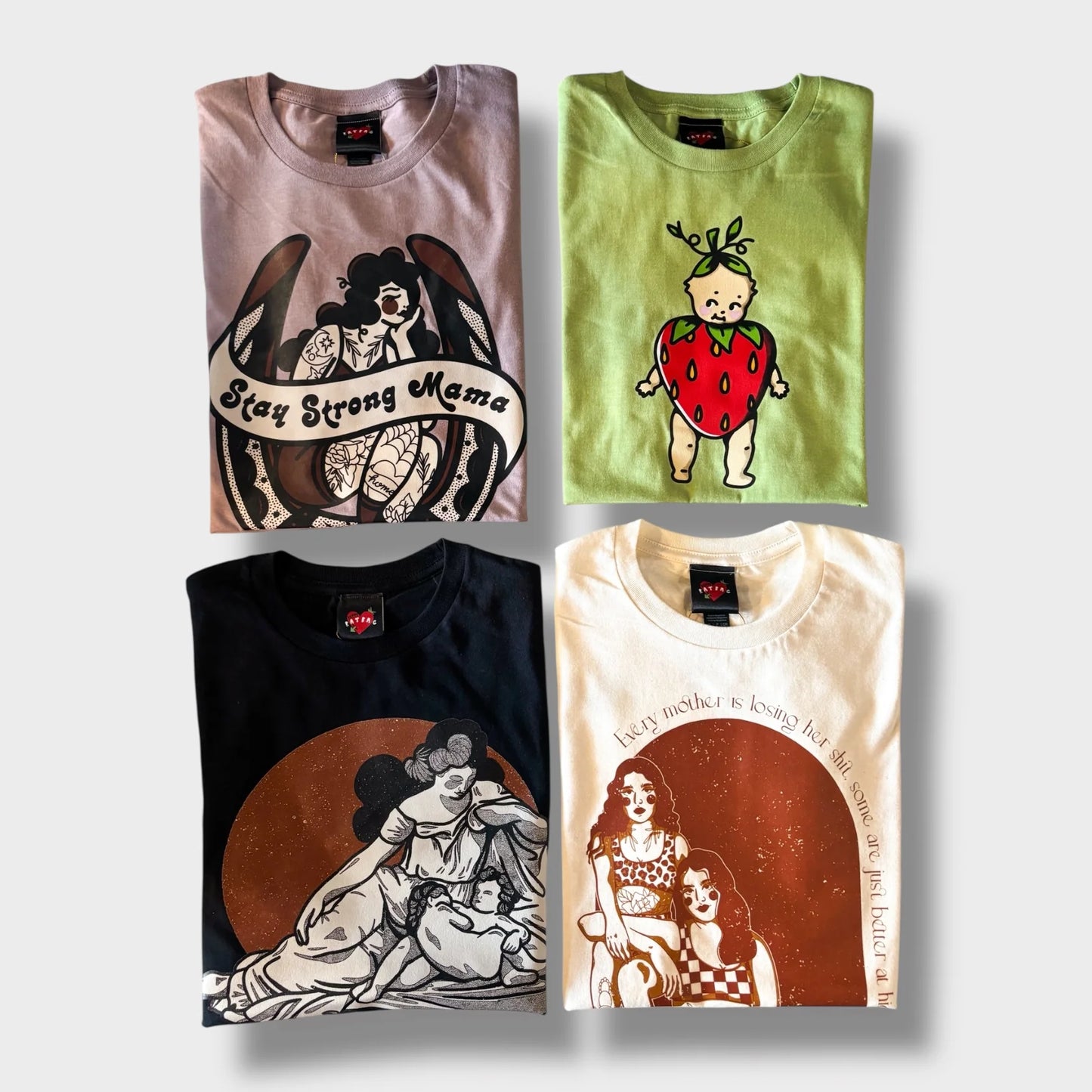 Four folded t-shirts with unique designs on a light gray background