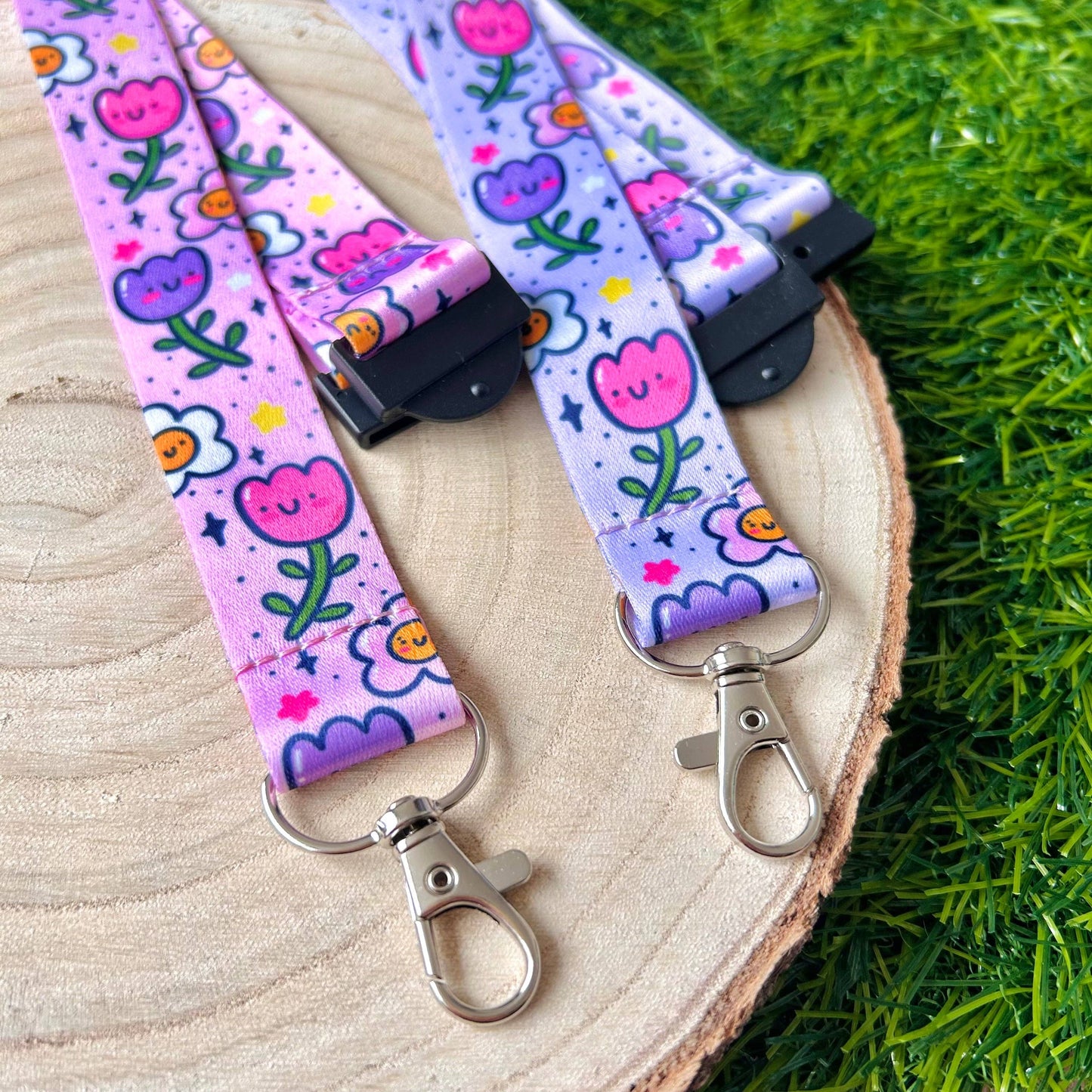 Floral patterned lanyard with keychain on a wooden surface with grass in the background