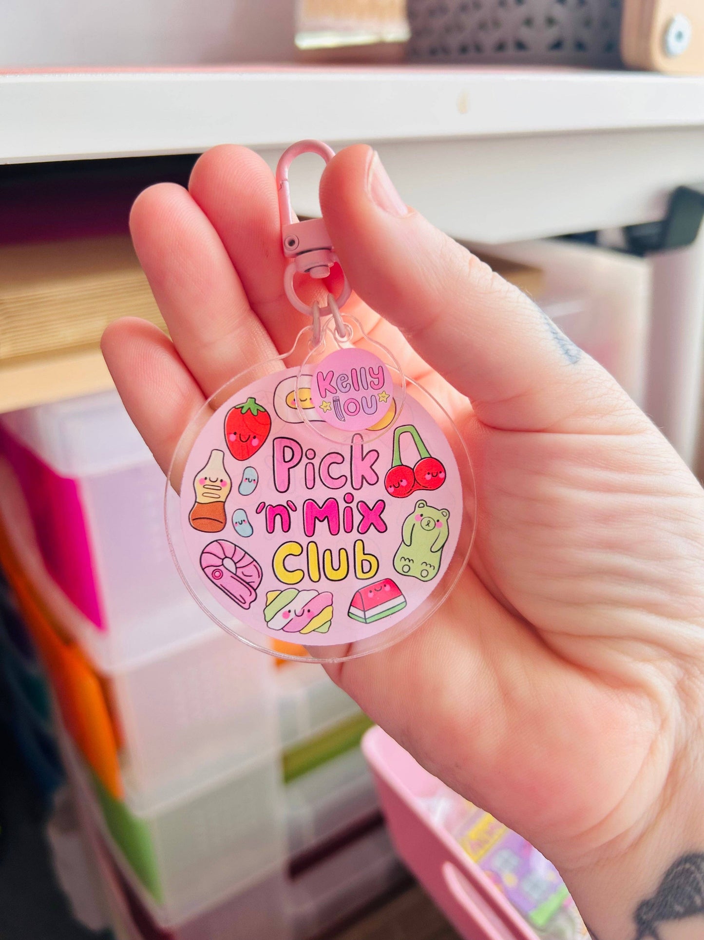 Hand holding a 'Pick 'n' Mix Club' keychain with colorful illustrations.