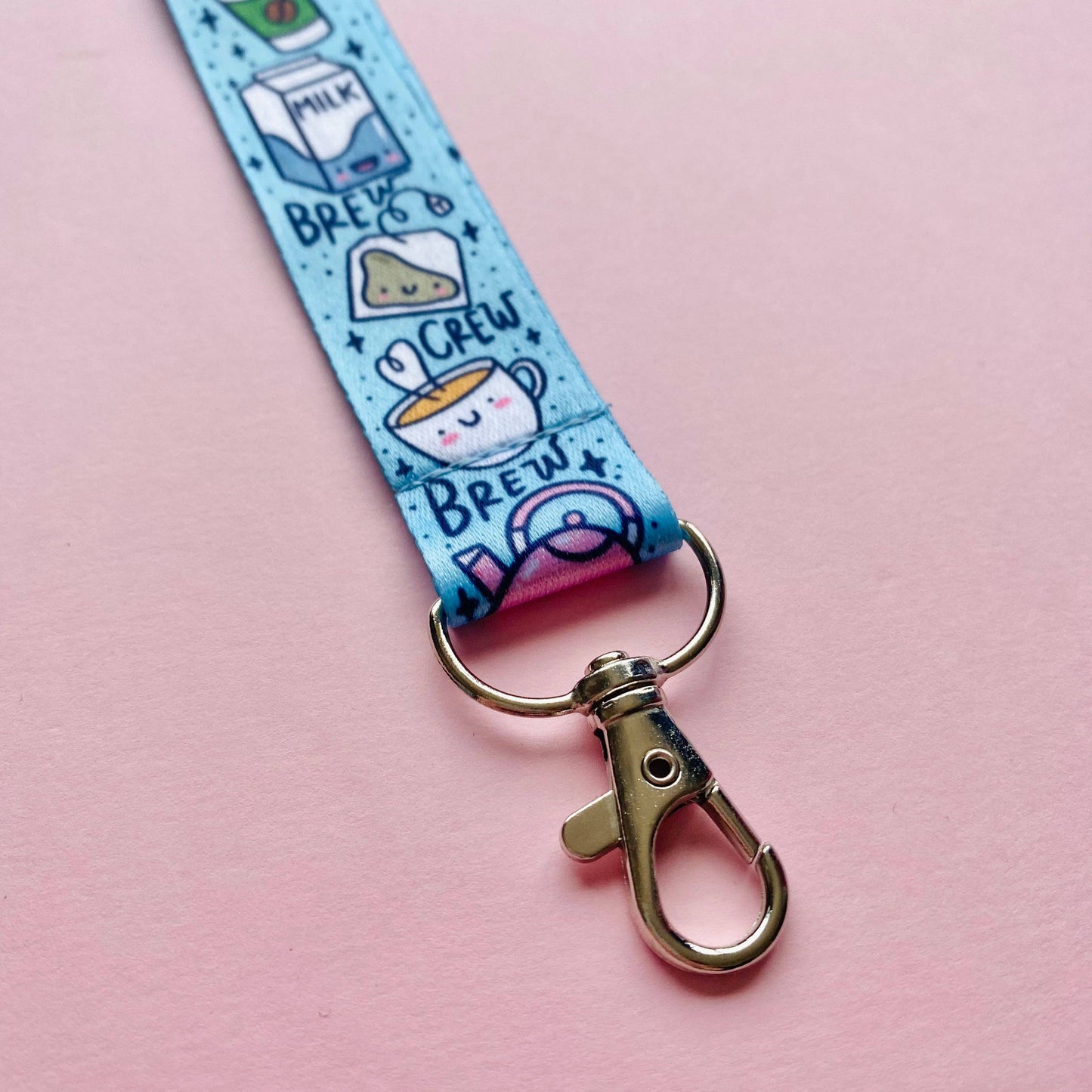 Keychain with cartoon designs on a blue strap against a pink background