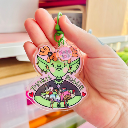 Hand holding a colorful keychain with a cartoon character and text