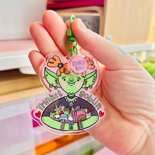 Hand holding a colorful keychain with a cartoon character and text