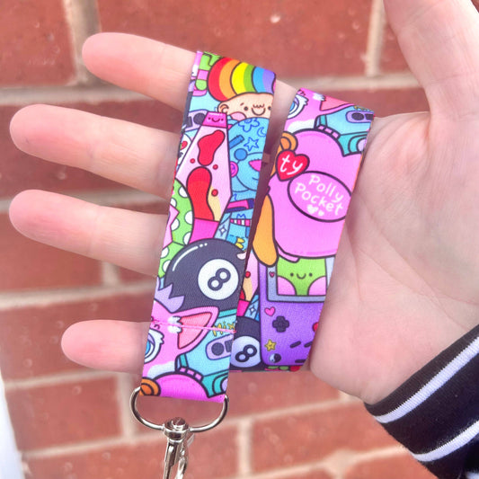 Colorful lanyard with cartoon designs held by a hand against a brick wall.