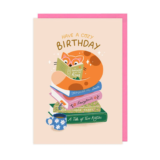 Birthday card with a fox reading books and a cup, on a pink border.