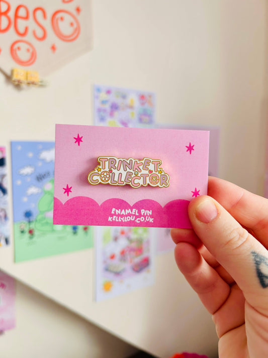 Hand holding a pink card with 'Trinket Collector' branding against a colorful background.