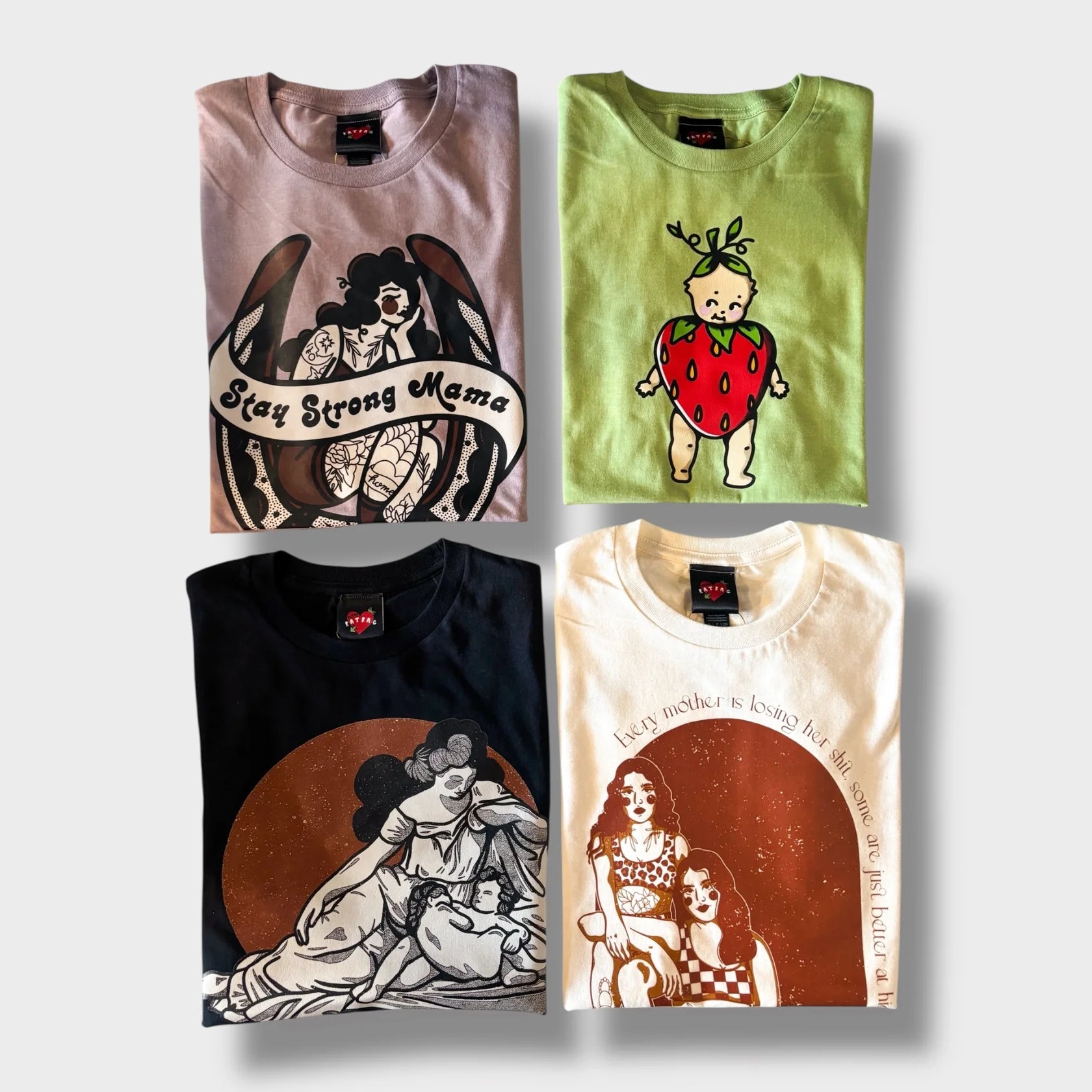 Four folded t-shirts with unique designs on a light gray background