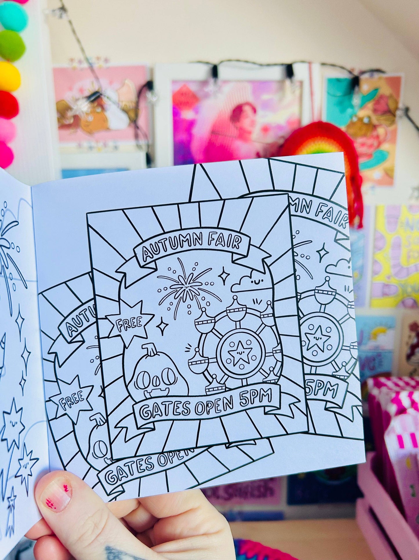 Coloring book with an autumn fair design held by a hand in a colorful room.