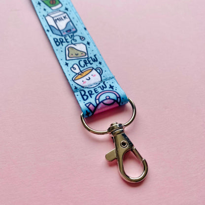 Keychain with cartoon designs on a blue strap against a pink background
